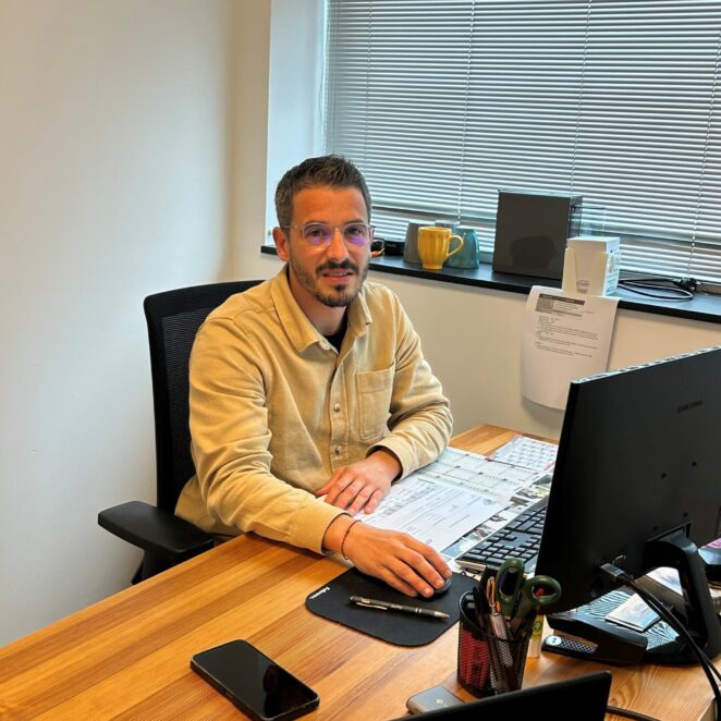 Mickael Galin pose devant son poste de travail équipé d'un ordinateur et de dossiers à la pépinière d'entreprises de Biron.