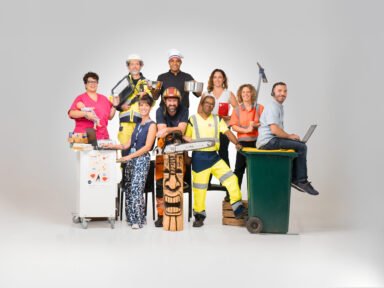 9 agents de la collectivité issus de métiers différents, posent en tenue de travail sur un fond uni. De gauche à droite, on voit une assistante maternelle avec un poupon dans la main gauche et un biberon dans la main droite, à côté un agent des services techniques avec des machines dans les mains qui ressemble à une tablette, à côté un cuisinier avec sa toque et deux récipient un dans chaque main, à côté une femme des services administratifs en tenue simple mais tenant en main le code de l'urbanisme, à côté une femme des services techniques avec une pioche dans les mains, à côté un agent d'accueil avec un micro-casque et un ordinateur sur les genoux, il est assis sur une poubelle au couvercle jaune. A gauche de la poubelle se tient un agent du service déchets tenant la poubelle, à sa gauche un agent des services techniques accoudé sur un totem de bois et tenant une tronçonneuse, et à sa gauche, une médiathécaire habillée décontracté avec un ordinateur devant elle et un support roulant avec une affiche du centre culturel Le MIX accroché dessus et transportant divers bouquins.